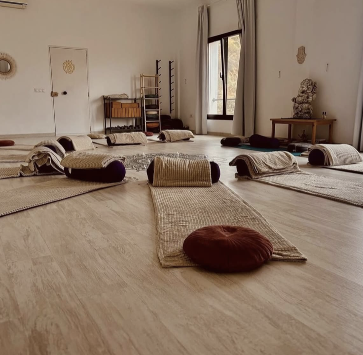 Yoga shala with mats and bolsters arranged on a wooden floor