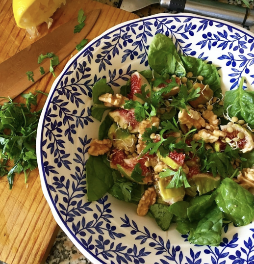 Fresh salad bowl with spinach, figs, walnuts and sprouts in a blue-and-white patterned dish